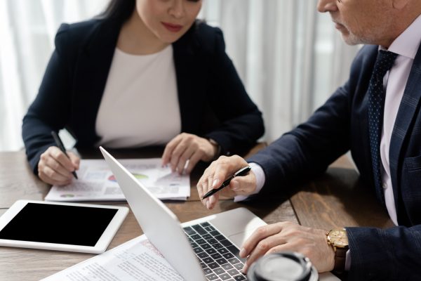 cropped view of businessman and businesswoman looking at laptop during business meeting